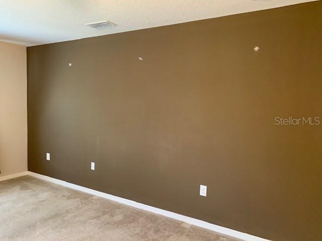 spare room with visible vents, light colored carpet, and baseboards