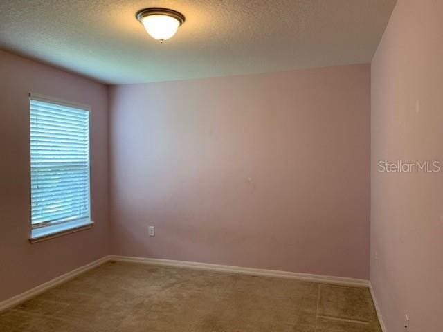 spare room with a textured ceiling and baseboards