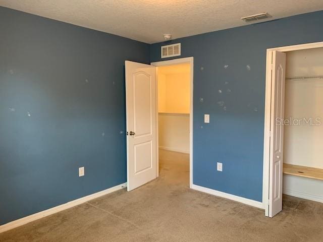 unfurnished bedroom featuring baseboards, visible vents, and a textured ceiling