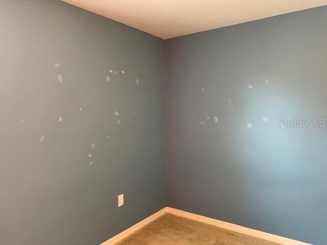 empty room featuring carpet and baseboards