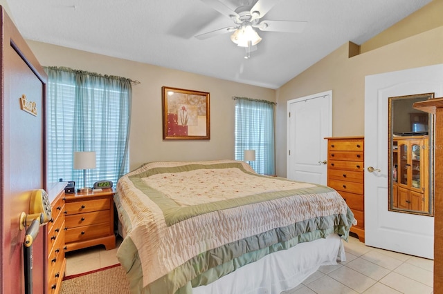 bedroom featuring multiple windows, vaulted ceiling, light tile patterned floors, and ceiling fan