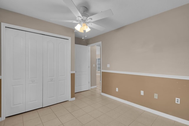 unfurnished bedroom with light tile patterned floors, a closet, a ceiling fan, and baseboards