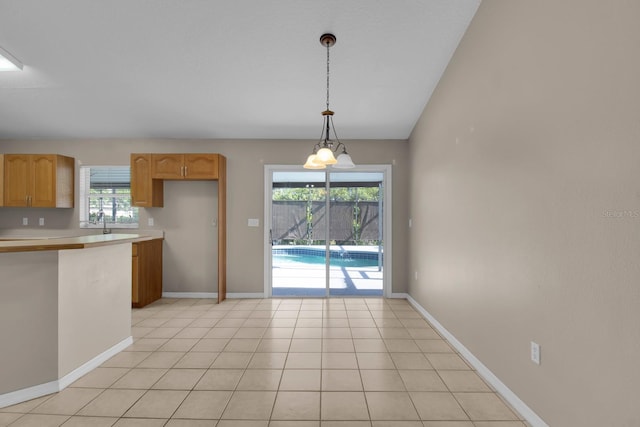 kitchen featuring baseboards, decorative light fixtures, a wealth of natural light, and light countertops
