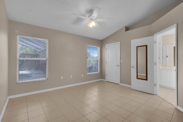 unfurnished bedroom with light tile patterned floors, multiple windows, vaulted ceiling, and baseboards