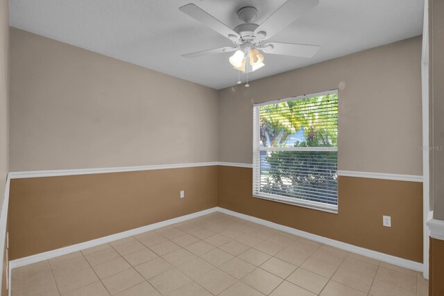 empty room with light tile patterned floors, ceiling fan, and baseboards