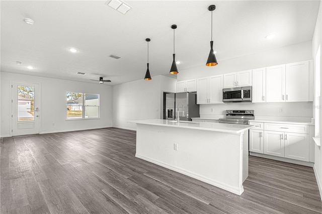 kitchen with a kitchen island with sink, decorative light fixtures, white cabinets, and appliances with stainless steel finishes