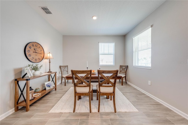 dining space featuring wood finish floors, visible vents, and baseboards