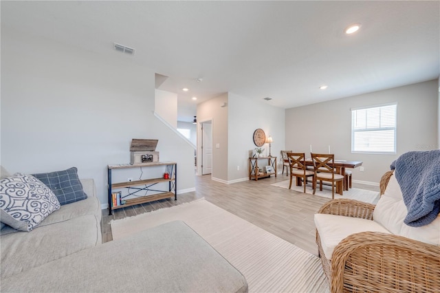 living area featuring recessed lighting, visible vents, baseboards, stairway, and light wood-type flooring