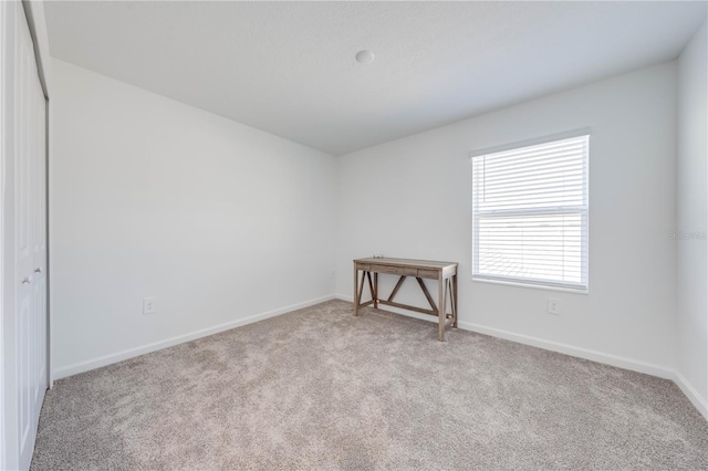 unfurnished room featuring light carpet and baseboards