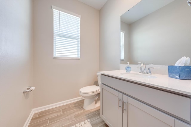 bathroom featuring wood finish floors, baseboards, vanity, and toilet