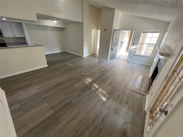 unfurnished living room featuring high vaulted ceiling, dark hardwood / wood-style floors, and a textured ceiling