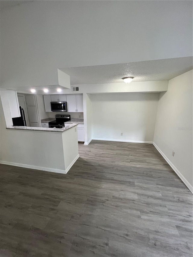 kitchen featuring appliances with stainless steel finishes, dark hardwood / wood-style floors, a textured ceiling, white cabinets, and kitchen peninsula