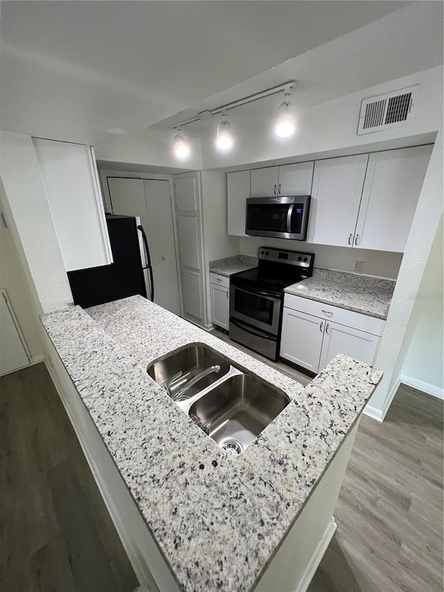 kitchen featuring sink, white cabinetry, kitchen peninsula, stainless steel appliances, and hardwood / wood-style floors