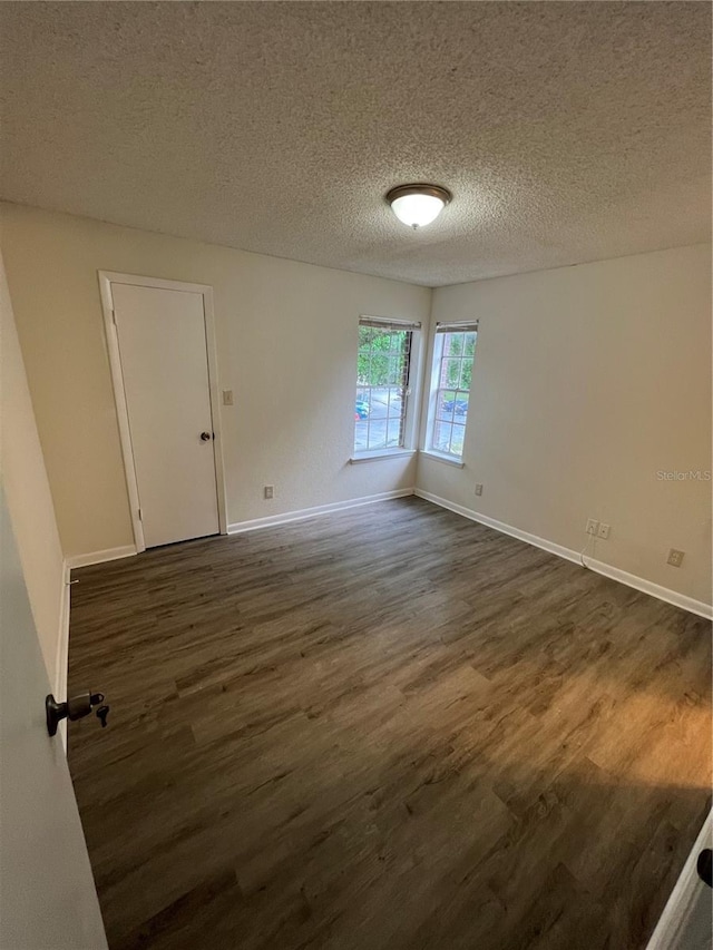 empty room with dark hardwood / wood-style flooring and a textured ceiling