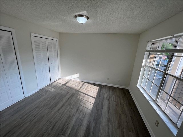 unfurnished bedroom featuring a textured ceiling and dark hardwood / wood-style flooring