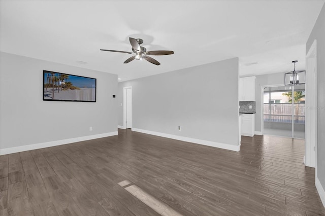 unfurnished living room featuring dark hardwood / wood-style flooring and ceiling fan with notable chandelier