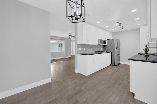 kitchen with stainless steel appliances, white cabinetry, decorative backsplash, and decorative light fixtures