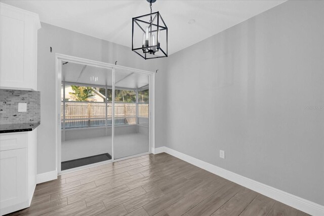 unfurnished dining area with a chandelier and light wood-type flooring