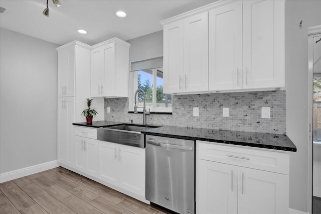 kitchen featuring sink, white cabinetry, dishwasher, dark stone counters, and decorative backsplash