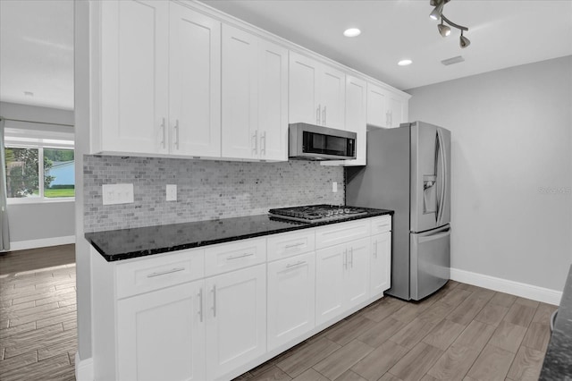 kitchen with dark stone countertops, appliances with stainless steel finishes, tasteful backsplash, and white cabinets