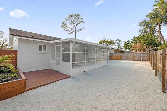 rear view of house featuring a sunroom and a deck