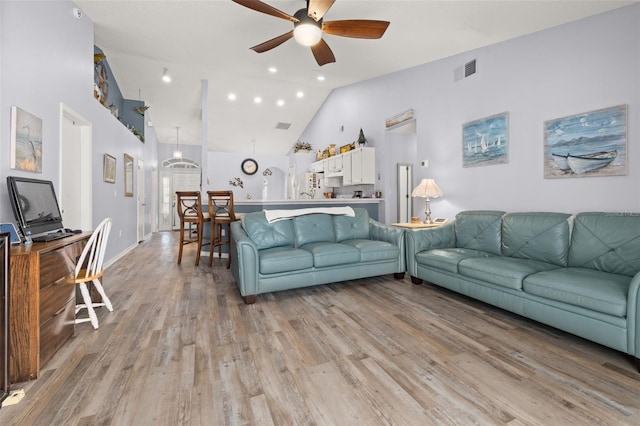 living room with high vaulted ceiling, ceiling fan, and light wood-type flooring