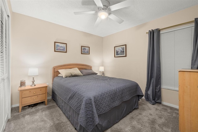 bedroom with ceiling fan, a closet, a textured ceiling, and carpet flooring