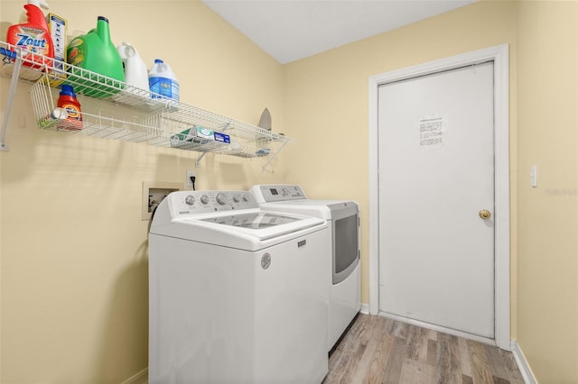 laundry area with washer and clothes dryer and light hardwood / wood-style floors