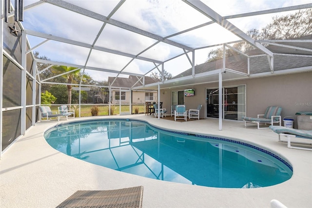 view of swimming pool featuring glass enclosure and a patio area