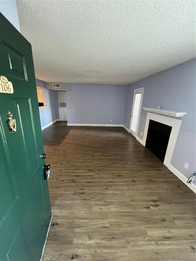 unfurnished living room with a tile fireplace, wood-type flooring, and a textured ceiling