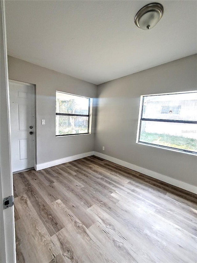 unfurnished room featuring light wood-type flooring and a healthy amount of sunlight