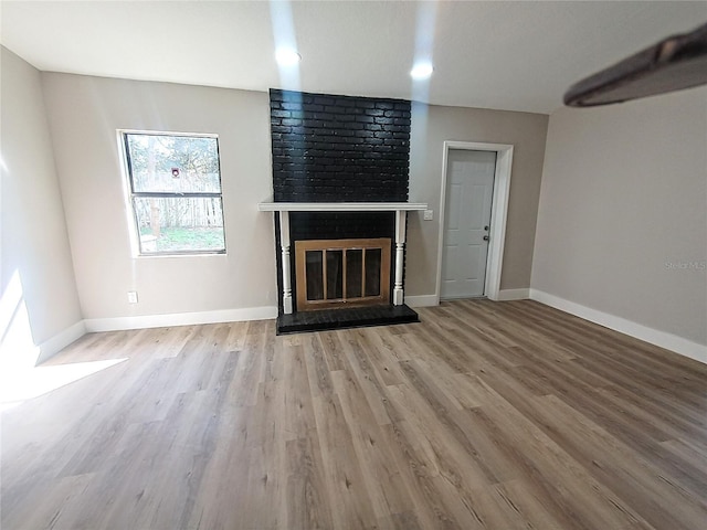 unfurnished living room featuring a brick fireplace and light hardwood / wood-style floors