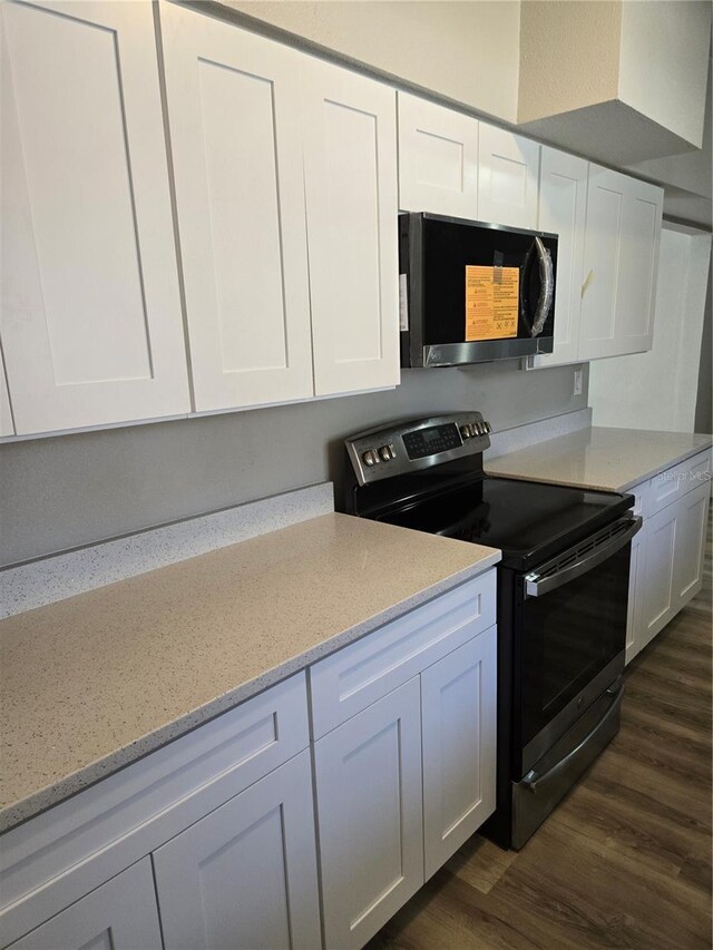 kitchen featuring dark hardwood / wood-style flooring, stainless steel electric range oven, light stone countertops, and white cabinets