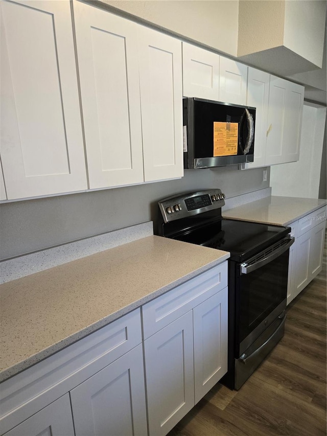 kitchen with electric range, white cabinets, dark hardwood / wood-style floors, and light stone counters