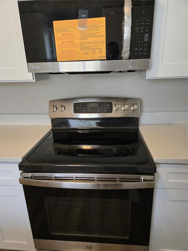 room details with appliances with stainless steel finishes and white cabinets