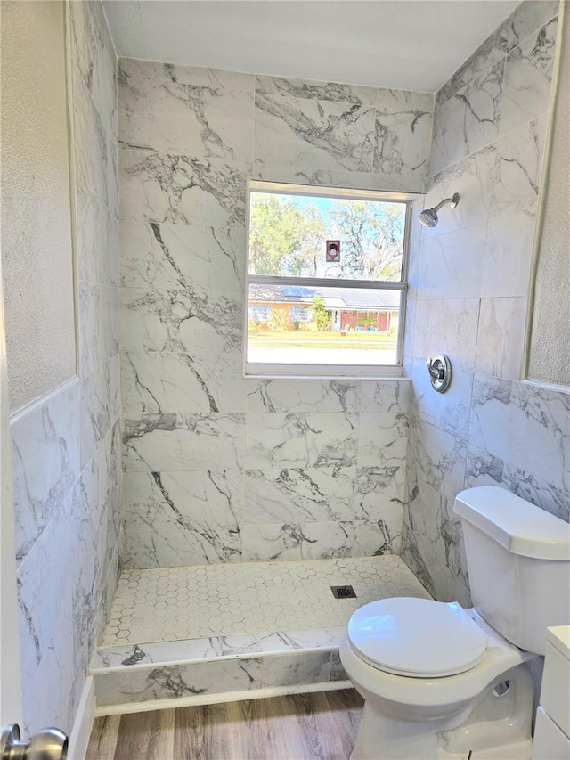 bathroom with a tile shower, tile walls, and wood-type flooring