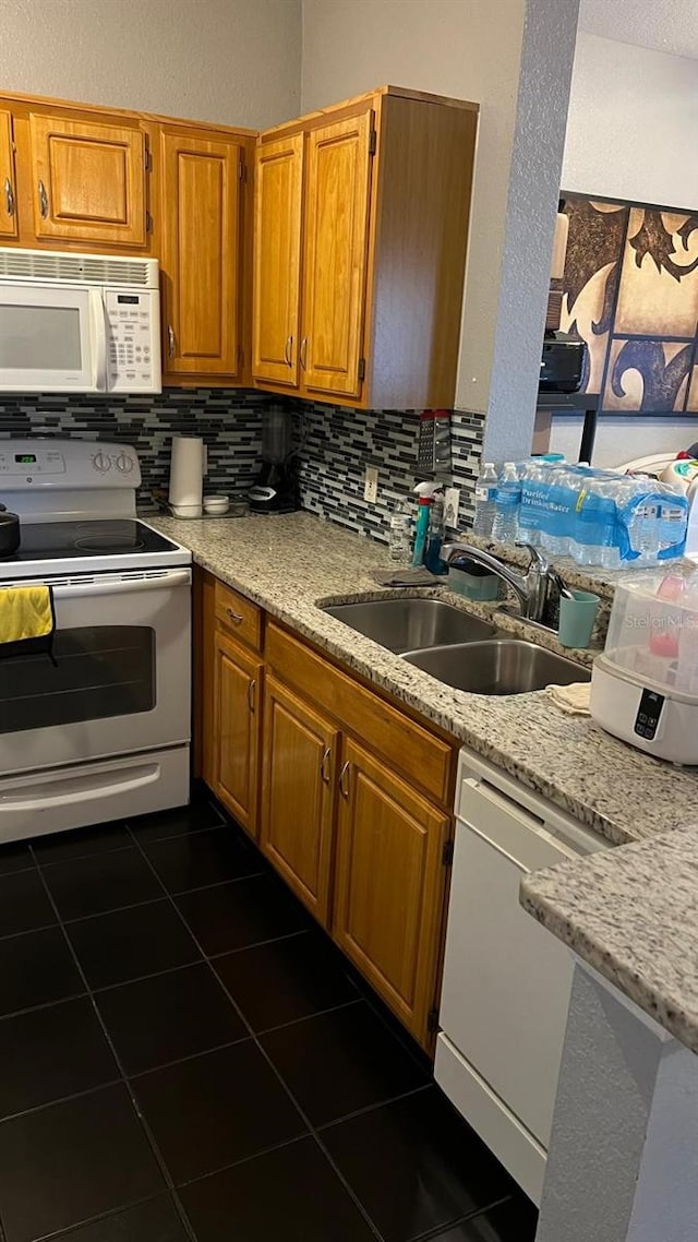 kitchen featuring white appliances, tasteful backsplash, brown cabinets, and a sink