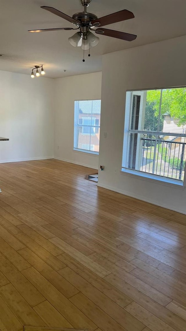 empty room featuring baseboards, ceiling fan, and wood finished floors
