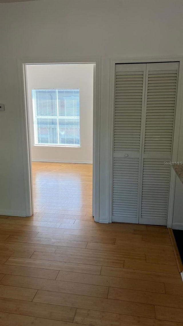 corridor with baseboards and light wood-style floors