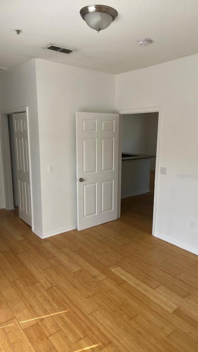 empty room featuring baseboards, visible vents, and light wood-style floors