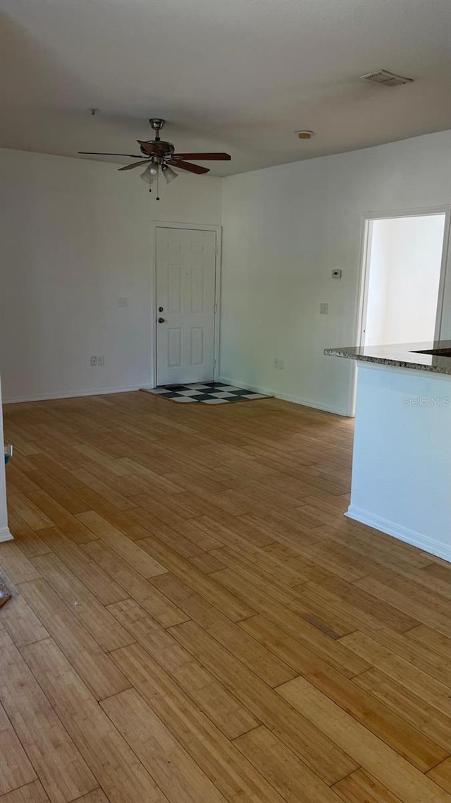 spare room with baseboards, visible vents, light wood-style floors, and a ceiling fan