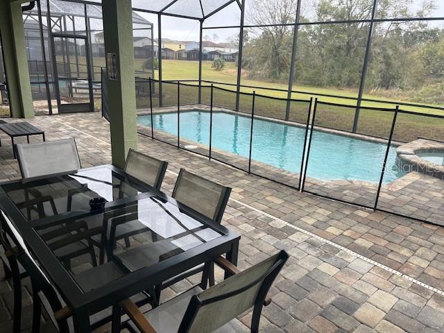 view of pool featuring a lanai, a patio area, and a pool with connected hot tub