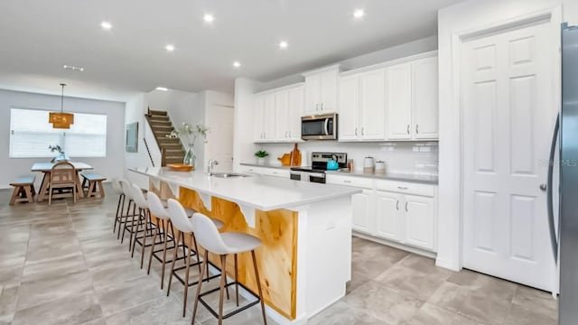 kitchen featuring hanging light fixtures, white cabinetry, appliances with stainless steel finishes, and light countertops