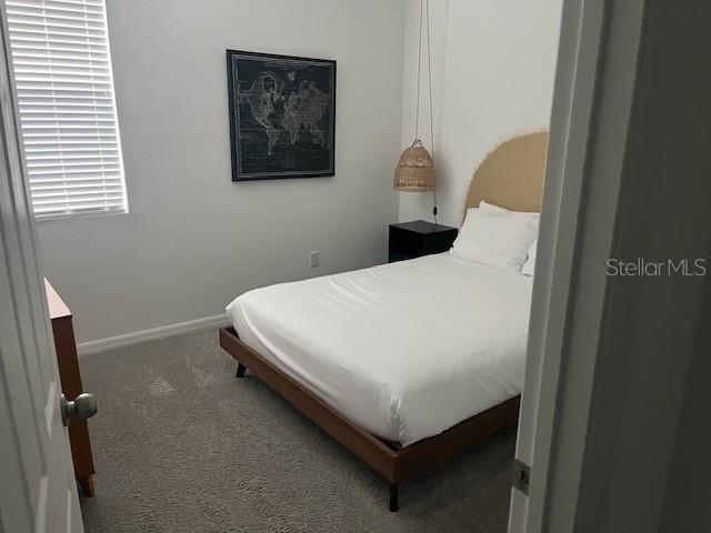 bedroom featuring dark carpet and baseboards