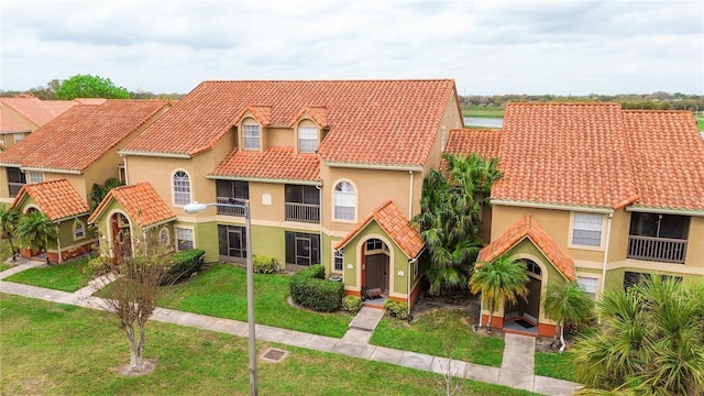 mediterranean / spanish-style house with a tiled roof, a front lawn, and stucco siding