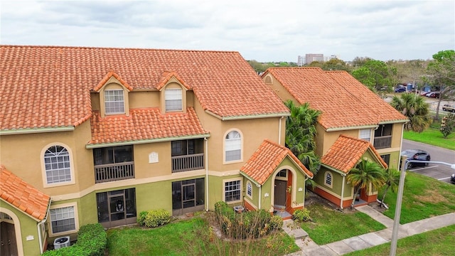 view of front of property featuring a tiled roof, a front lawn, and stucco siding