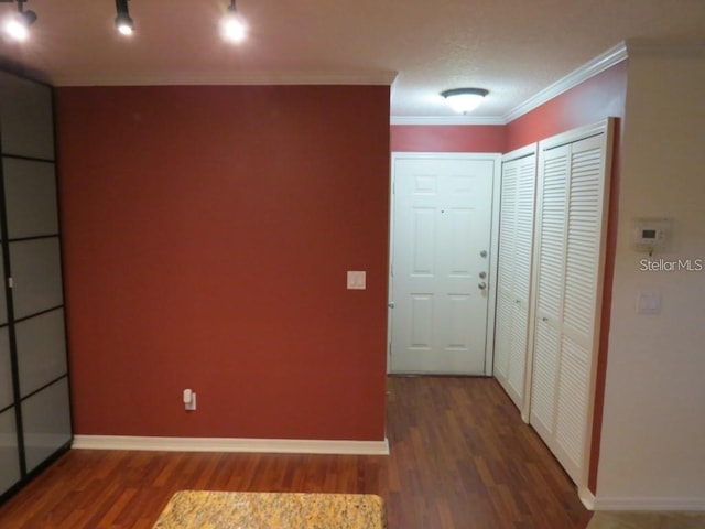 interior space featuring track lighting, wood finished floors, baseboards, and ornamental molding