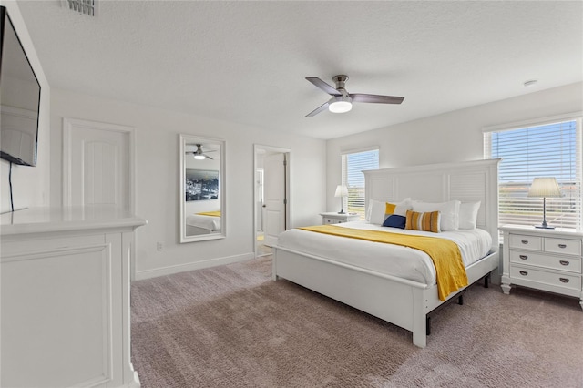 carpeted bedroom featuring multiple windows, ceiling fan, and a textured ceiling