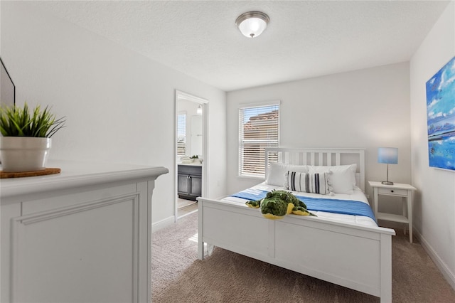 carpeted bedroom with connected bathroom and a textured ceiling