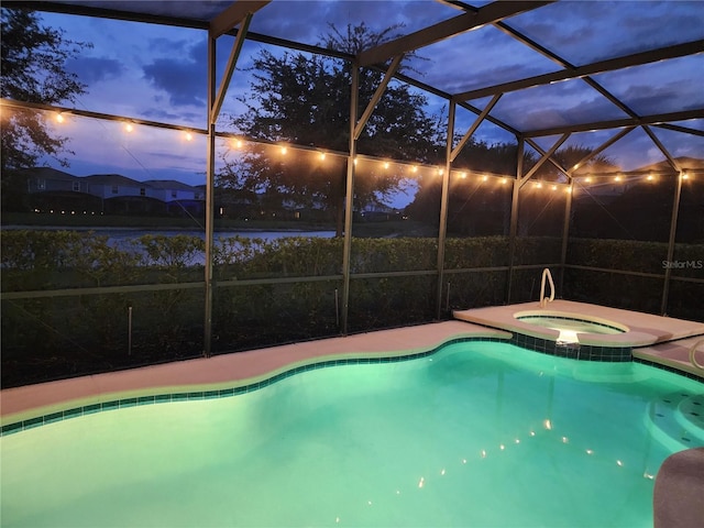 pool at dusk featuring an in ground hot tub and a lanai